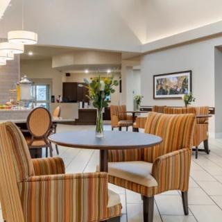A cozy and well-lit hotel dining area with striped chairs and round tables.