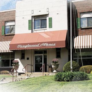 The exterior of a building with an awning displaying its name, featuring steps leading to the entrance.