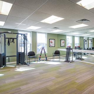 A well-lit gym with fitness equipment and mirrors lining the walls.