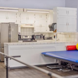 A well-equipped kitchen area in a rehabilitation setting, featuring modern appliances and exercise equipment.