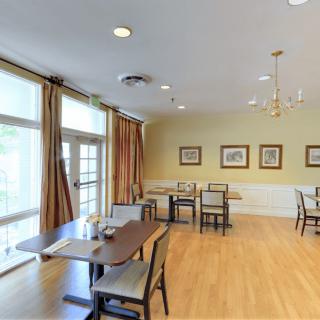 A cozy dining room with wooden floors, tables, and framed artwork on the walls.