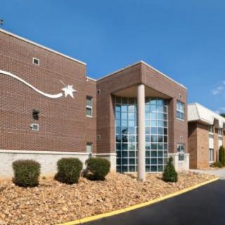 A modern brick building with a glass entrance under a clear blue sky.