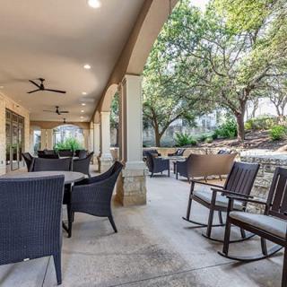 A spacious outdoor patio with comfortable seating, surrounded by lush greenery.