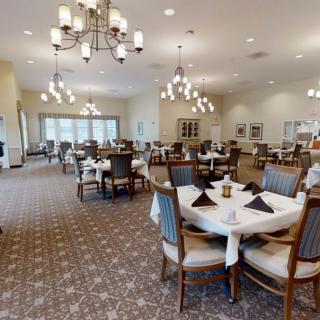 An elegant dining room with neatly arranged tables and decorative chandeliers.