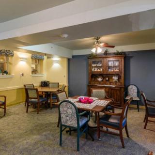 A cozy dining room with a wooden table and chairs, featuring a decorative cabinet and warm lighting.