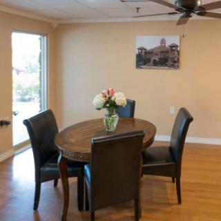 A cozy dining room with a wooden table surrounded by four chairs, adorned with flowers in a vase.