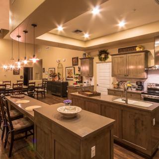 A modern kitchen with a spacious dining area, featuring wooden cabinets and elegant pendant lighting.