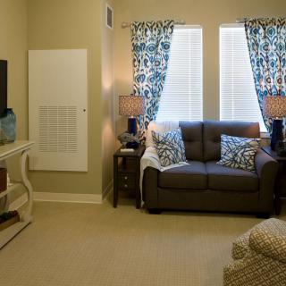 A cozy living room with a sofa, patterned curtains, and a television.