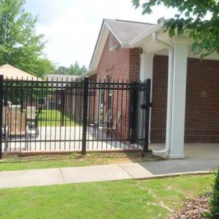 A gated entrance to a brick building with an outdoor patio and lawn.
