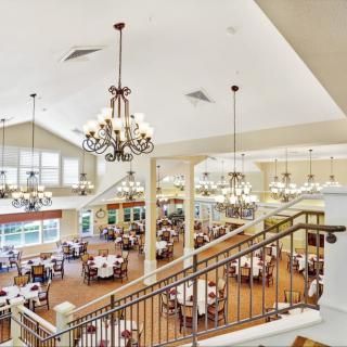 Spacious dining hall with elegant chandeliers and multiple tables.