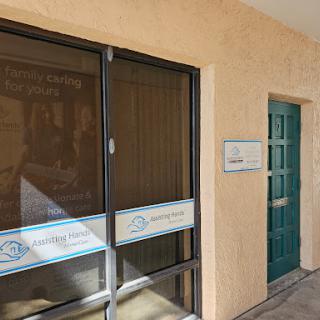 A view of a building's entrance featuring a green door and a window with signage.