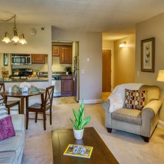 A cozy and modern apartment living room with a view into an open kitchen and dining area.