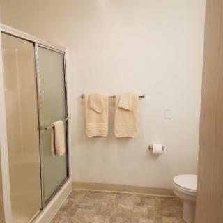 A clean and simple bathroom with a shower, towels, and toilet.