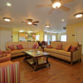 A cozy living room with matching sofas and a coffee table, featuring ceiling fans and warm lighting.