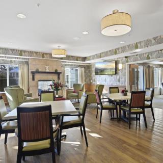 A modern dining area with multiple tables and chairs, featuring stylish lighting and a wooden floor.