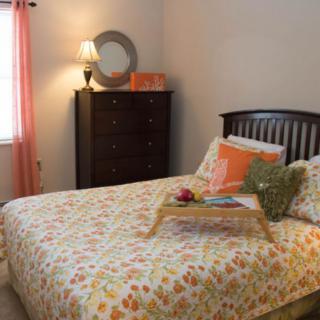 A cozy bedroom with a colorful bedspread and decorative elements.