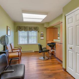 A cozy hair salon with modern decor featuring wooden floors and green walls.