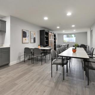 A modern meeting room with long tables and chairs arranged for a conference setup.