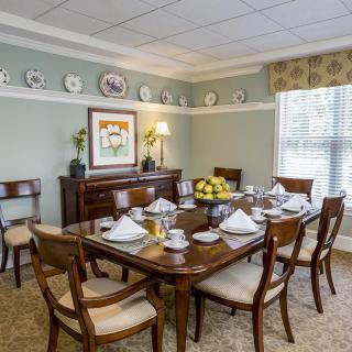 A formal dining room with a set table, elegant chairs, and tasteful decor.