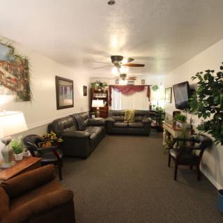 A cozy living room with sofas, a TV, indoor plants, and wall decorations.