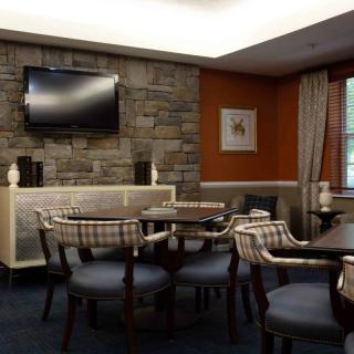 A modern lounge area featuring a stone wall, television, and comfortable seating with tables.