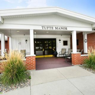 The entrance to Tuft's Manor featuring a welcoming porch with seating.