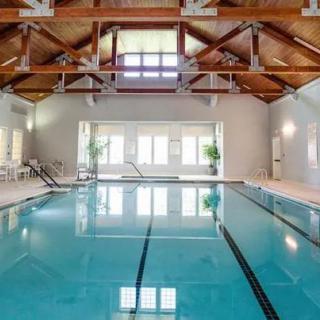 An inviting indoor swimming pool with wooden beam architecture and large windows.