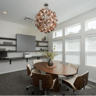A modern office conference room with a round table and stylish chandelier.