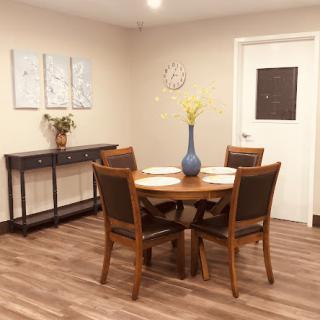 A cozy dining room featuring a wooden table, chairs, and decorative elements on the walls.