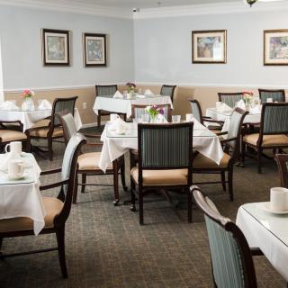 An elegantly arranged dining room with white tablecloths and neatly set tables and chairs.