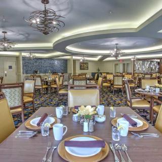 An elegantly set dining room with multiple tables, chairs, and chandeliers.