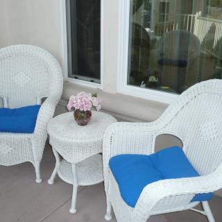 A cozy patio setup with wicker chairs, a small table, and blue cushions.