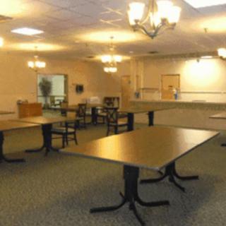 An empty room with tables, chairs, and chandeliers.