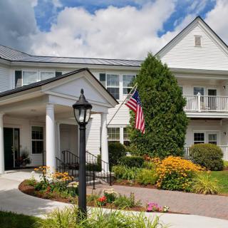 A beautiful house with a manicured garden and an American flag flying on the porch.