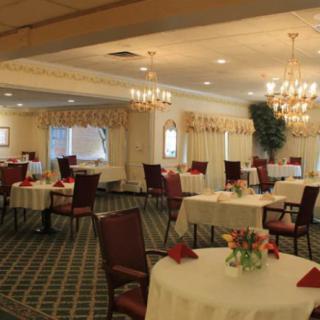 An elegant dining room with round tables and chandeliers.