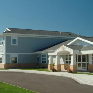 A modern residential building with a driveway and landscaped lawn.
