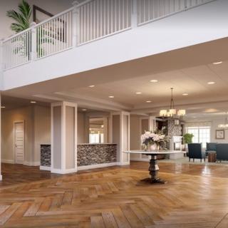 A spacious and elegantly designed living room featuring wooden flooring, a chandelier, and an open balcony railing.