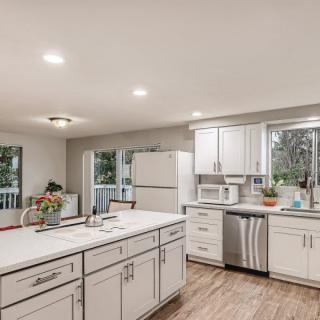A modern kitchen with white cabinets, a spacious island, and wood flooring.