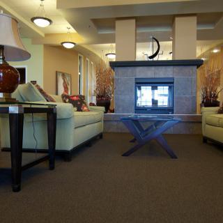 A cozy living room with modern decor featuring sofas, a central fireplace, and ambient lighting.