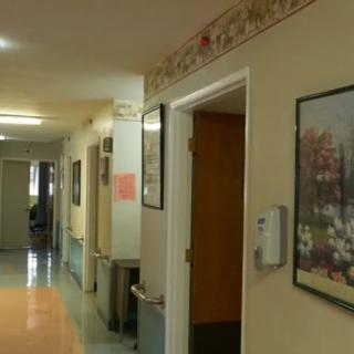 A hospital corridor with artwork on the walls and open doors.