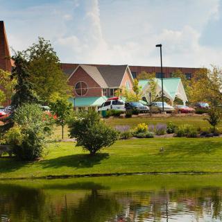 A scenic view of a building surrounded by greenery and a pond.