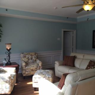 A cozy living room with a sofa, floral chair, and ceiling fan.