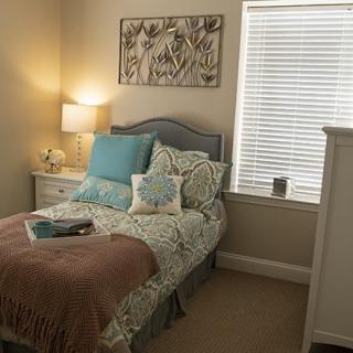 A cozy, well-decorated bedroom with a bed, lamp, and artwork on the wall.
