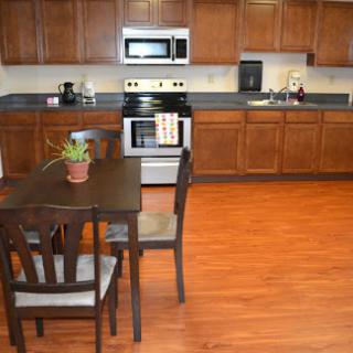 A modern kitchen featuring wooden cabinets, a dining table with chairs, and various appliances.