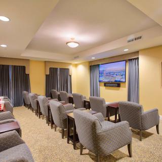 A cozy home theater setup with multiple rows of comfortable chairs facing a wall-mounted television.