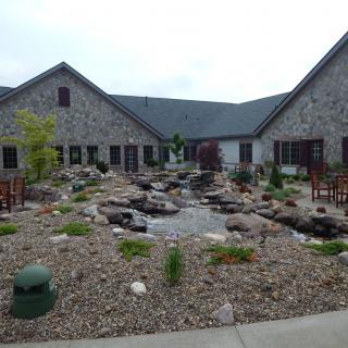 A landscaped courtyard with stones and plants surrounded by a building.