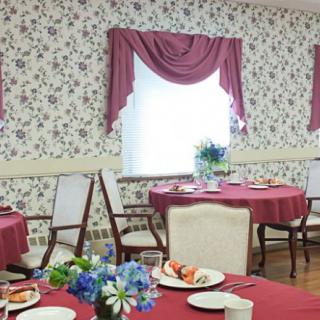 A cozy dining room with floral wallpaper and elegantly set tables.