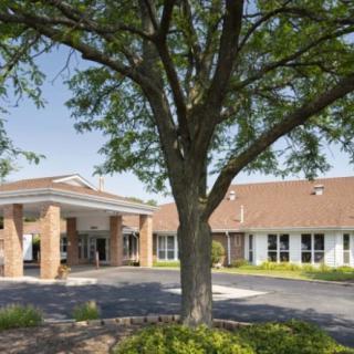 A view of a building exterior with a large tree in the foreground.