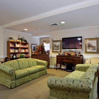 A cozy living room with green sofas, a bookshelf, and a television.