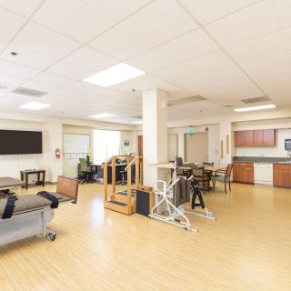 A bright and spacious physical therapy room with various exercise equipment and seating areas.